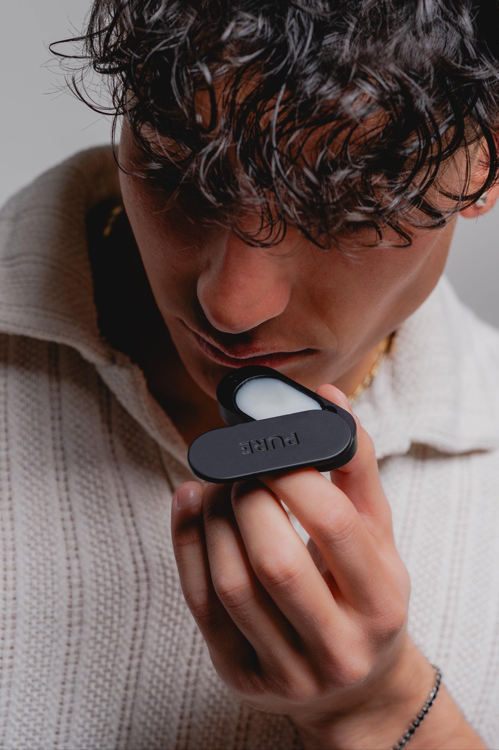 A boy smelling a black PURE Solid perfume box